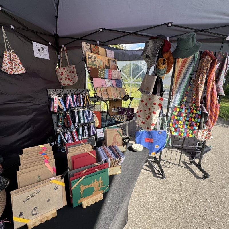Verkaufsstand mit handgemachten Karten, Schlüsselbändern, Büchern, Schals, Hüten im Pavillon