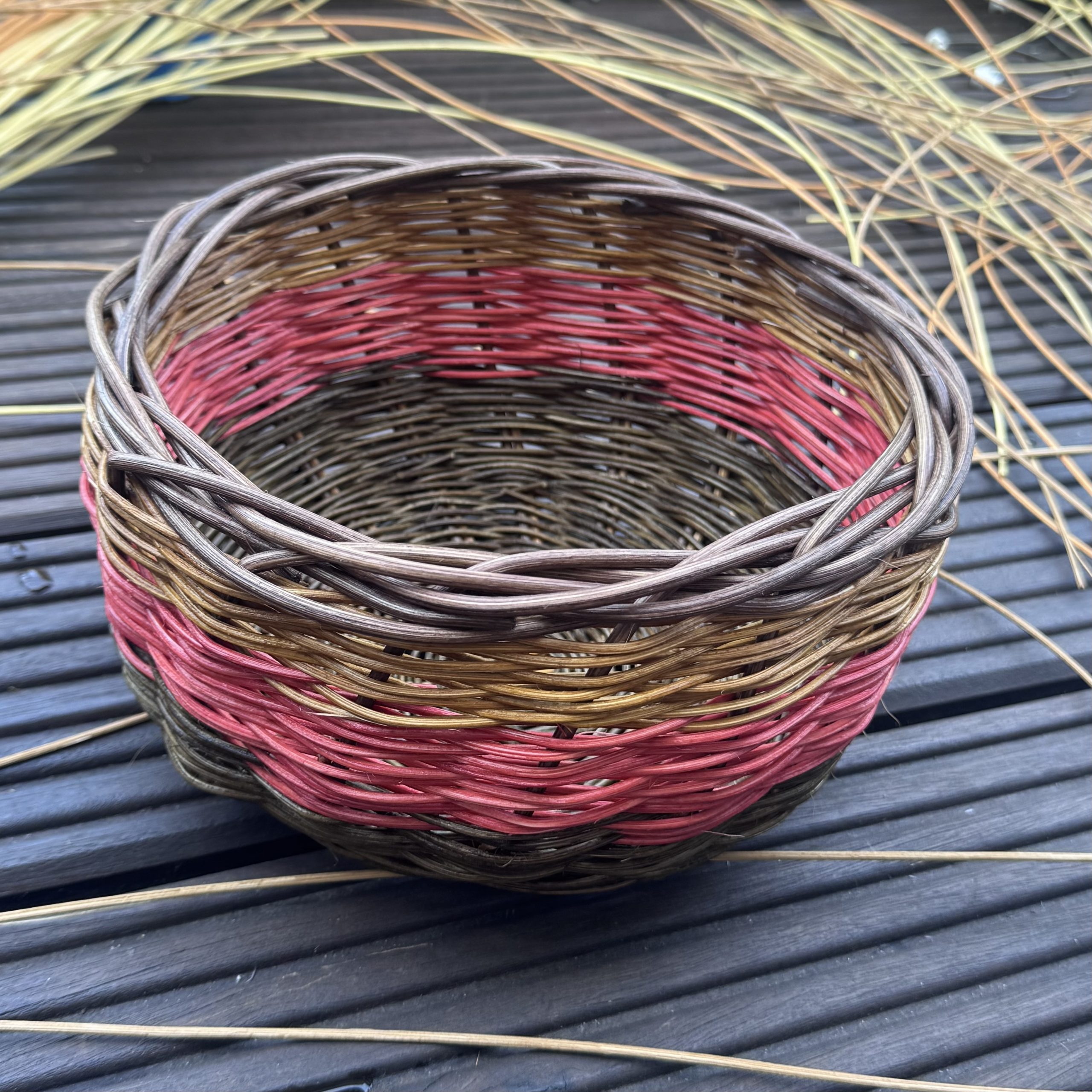 Korb aus farbigem Peddigrohr in Braun- und Rottönen