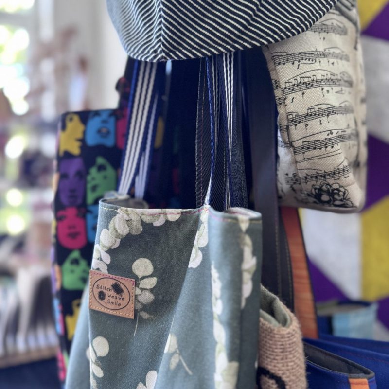 Nahaufnahme von Stofftaschen, am oberen Bildrand ein blau-weiß gestreifter Hut