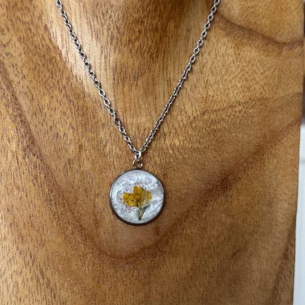 Kette mit orangener Trockenblume auf perlmuttfarbenem UV Resin in silberfarbener, runder Lünette