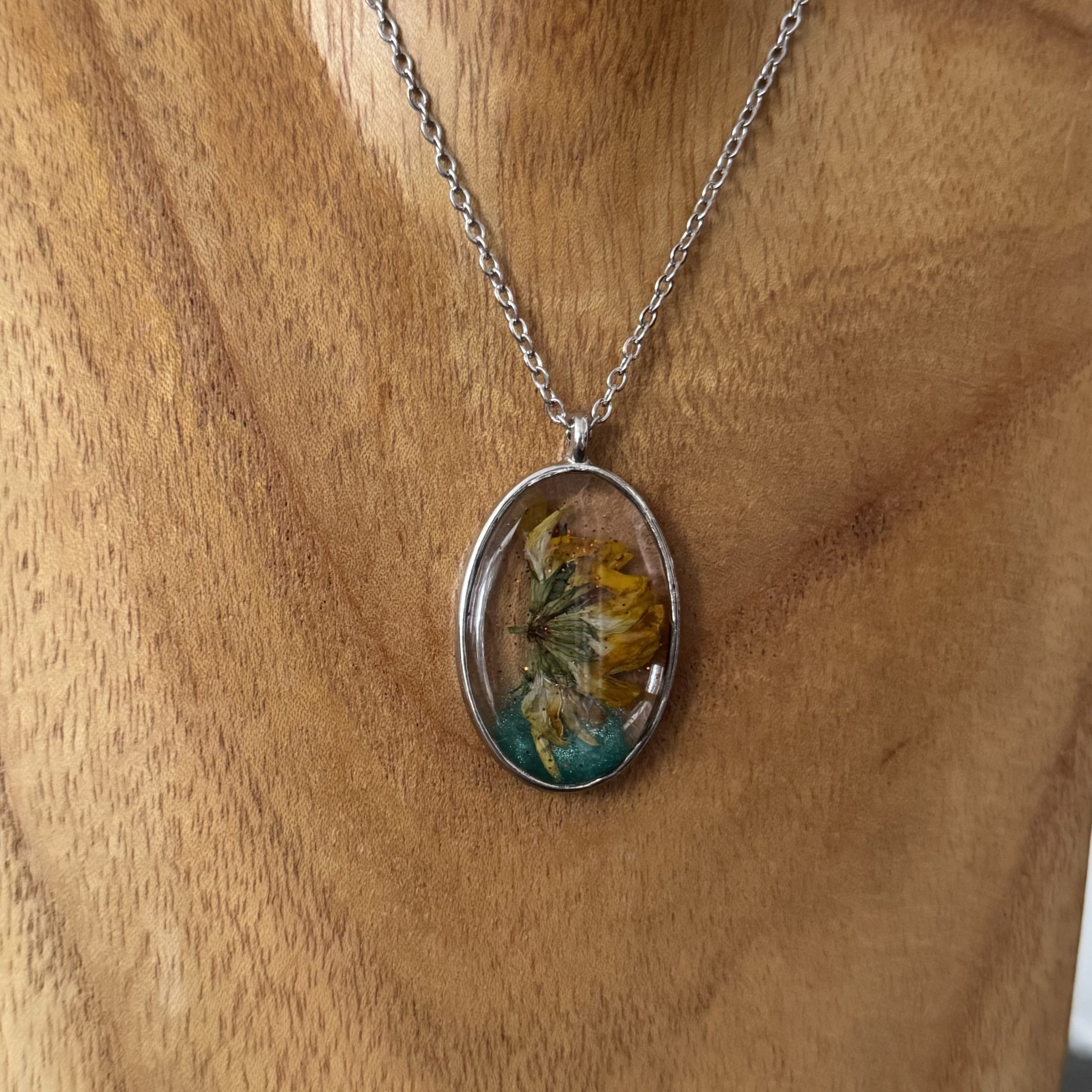Kette mit in UV Resin eingegossener Trockenblume in silberfarbenem, ovalem Rahmen