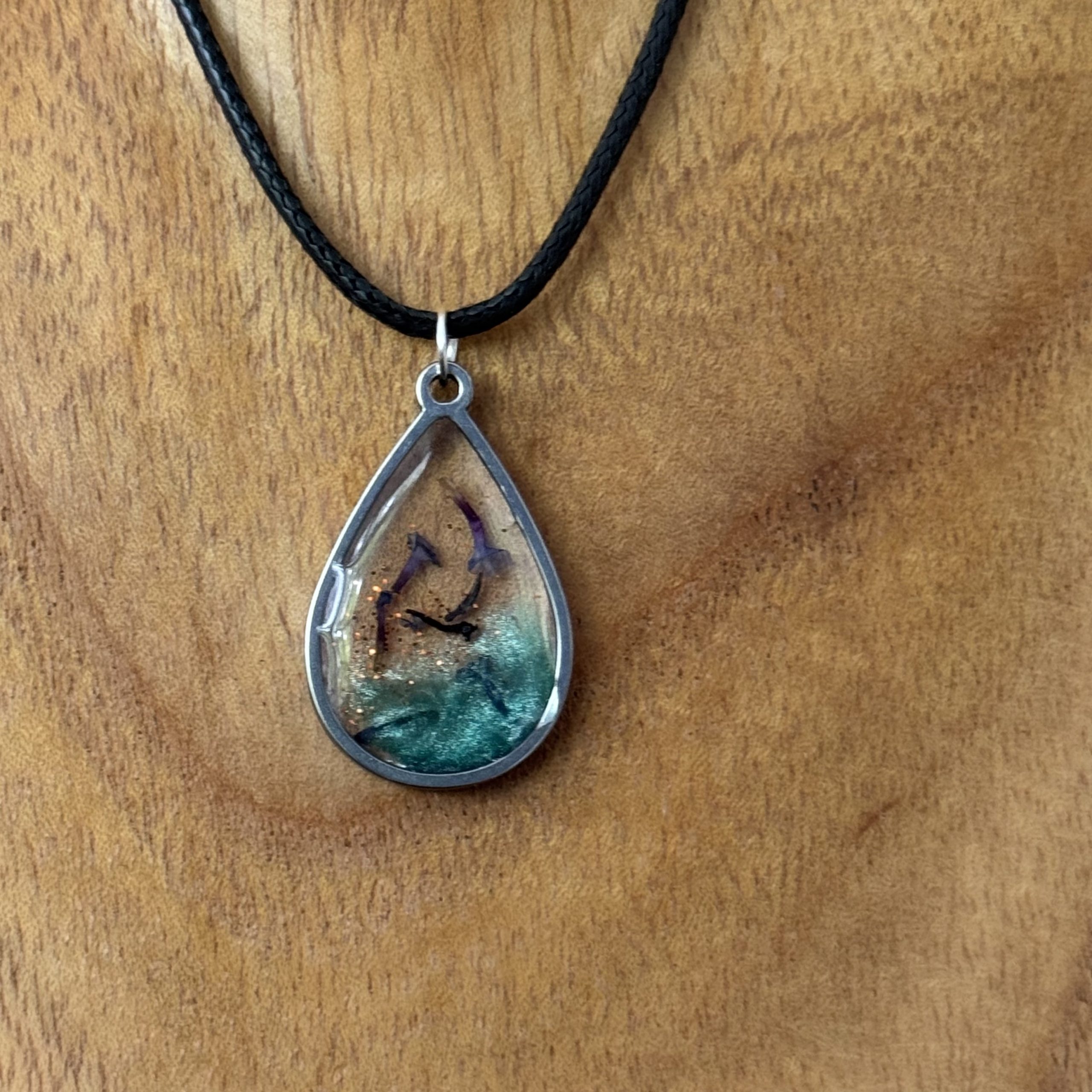 Kette mit in UV Resin eingegossener Trockenblume in silberfarbenem, tropfenförmigem Rahmen