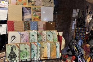 Verkaufsstand Hagen 2025_11-4 ©StitchWeaveSmile Verkaufsstand vor Backsteinwand mit Büchern, Taschen, Schmuck, Körben