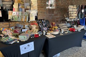 Verkaufsstand vor Backsteinwand mit Büchern, Taschen, Schmuck, Körben