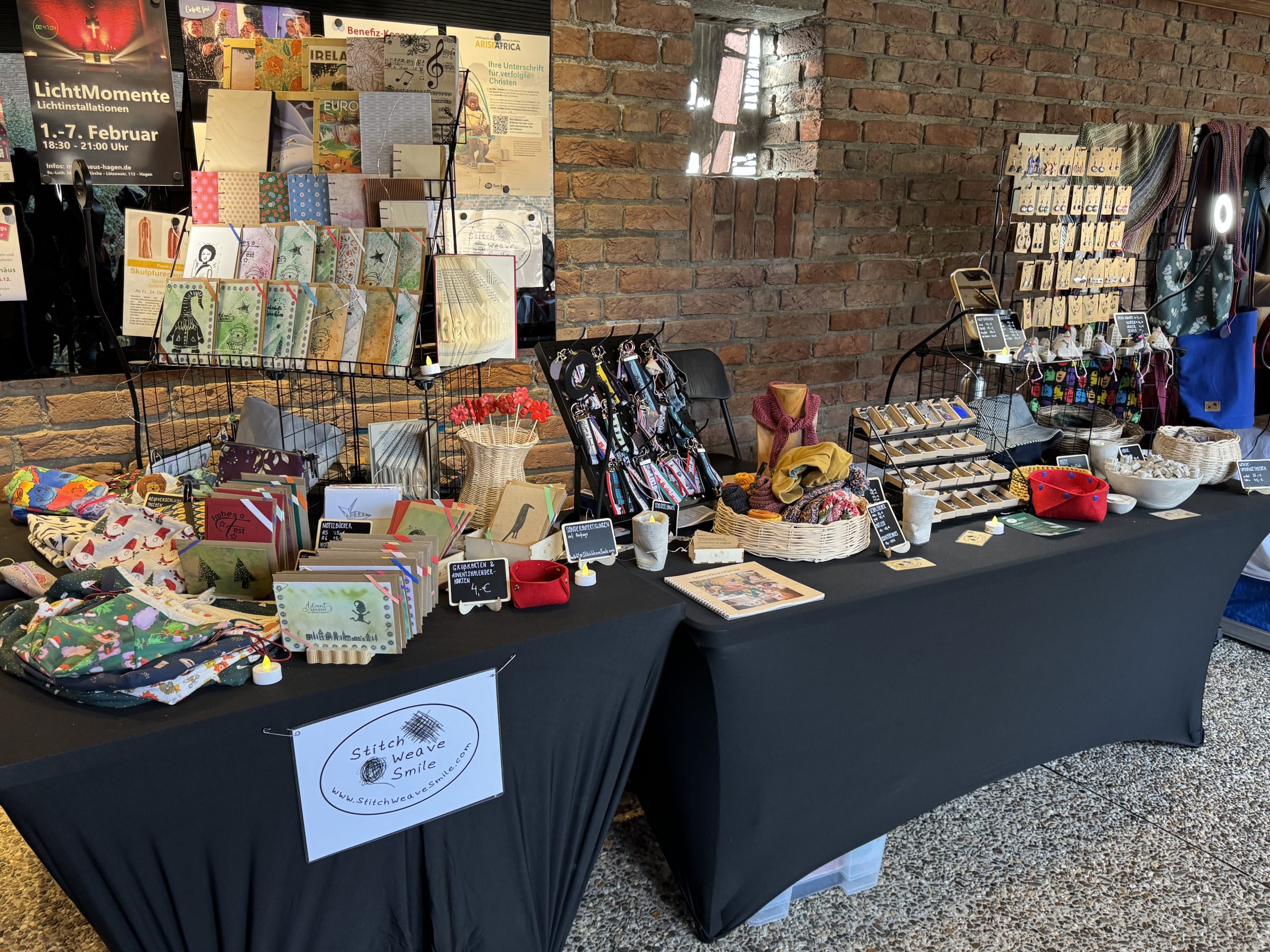 Verkaufsstand Hagen 2025_11-5 ©StitchWeaveSmile Verkaufsstand vor Backsteinwand mit Büchern, Taschen, Schmuck, Körben