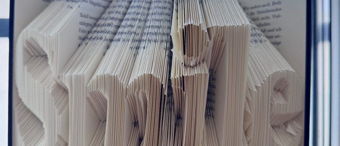 Hardcover Buch in dessen Seiten das Wort „Smile“ gefaltet wurde.