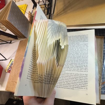 In die Seiten eines Buches wird ein W gefaltet